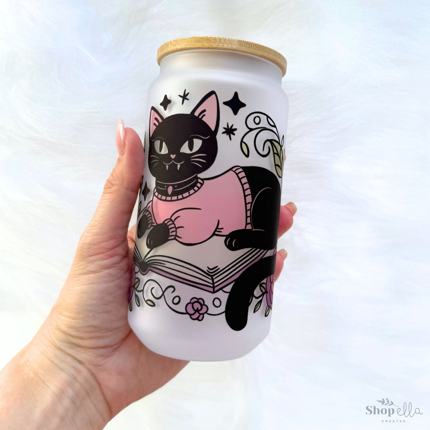 a hand holding a white can with a black cat on it