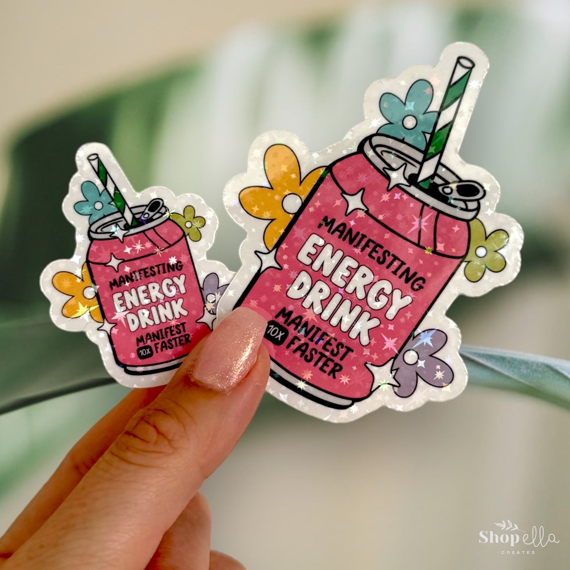 a sticker of a pink drink with a green straw that says manifesting energy drink manifest 10x faster holographic
