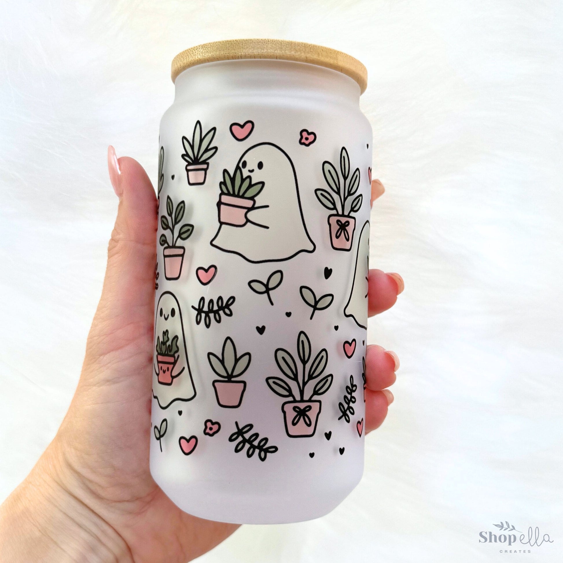 a hand holding a white can with plants on it