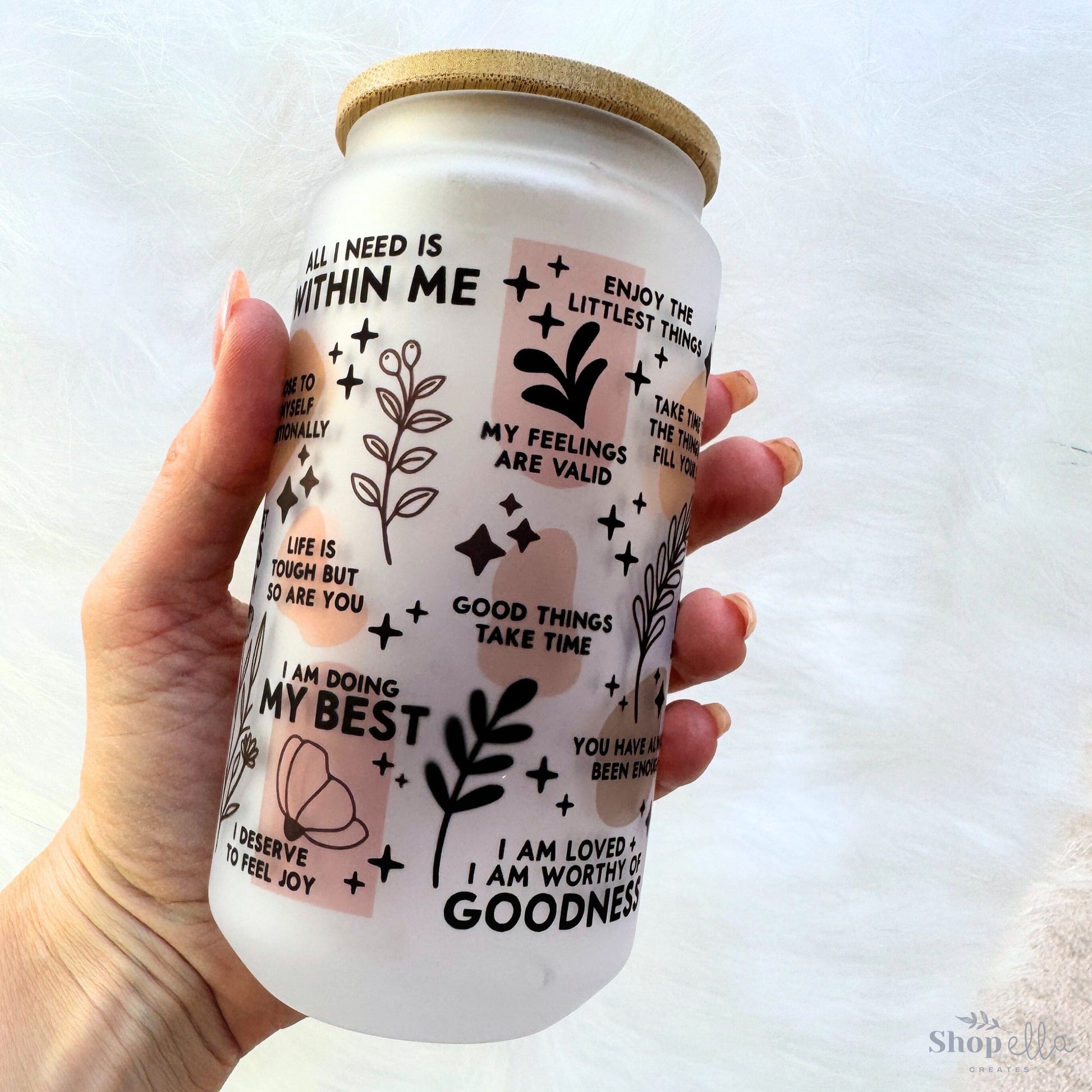 a hand holding a white coffee cup with stickers on it
