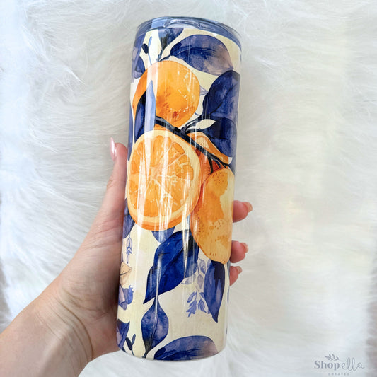 a hand holding a blue and yellow tumbler with lemons on it