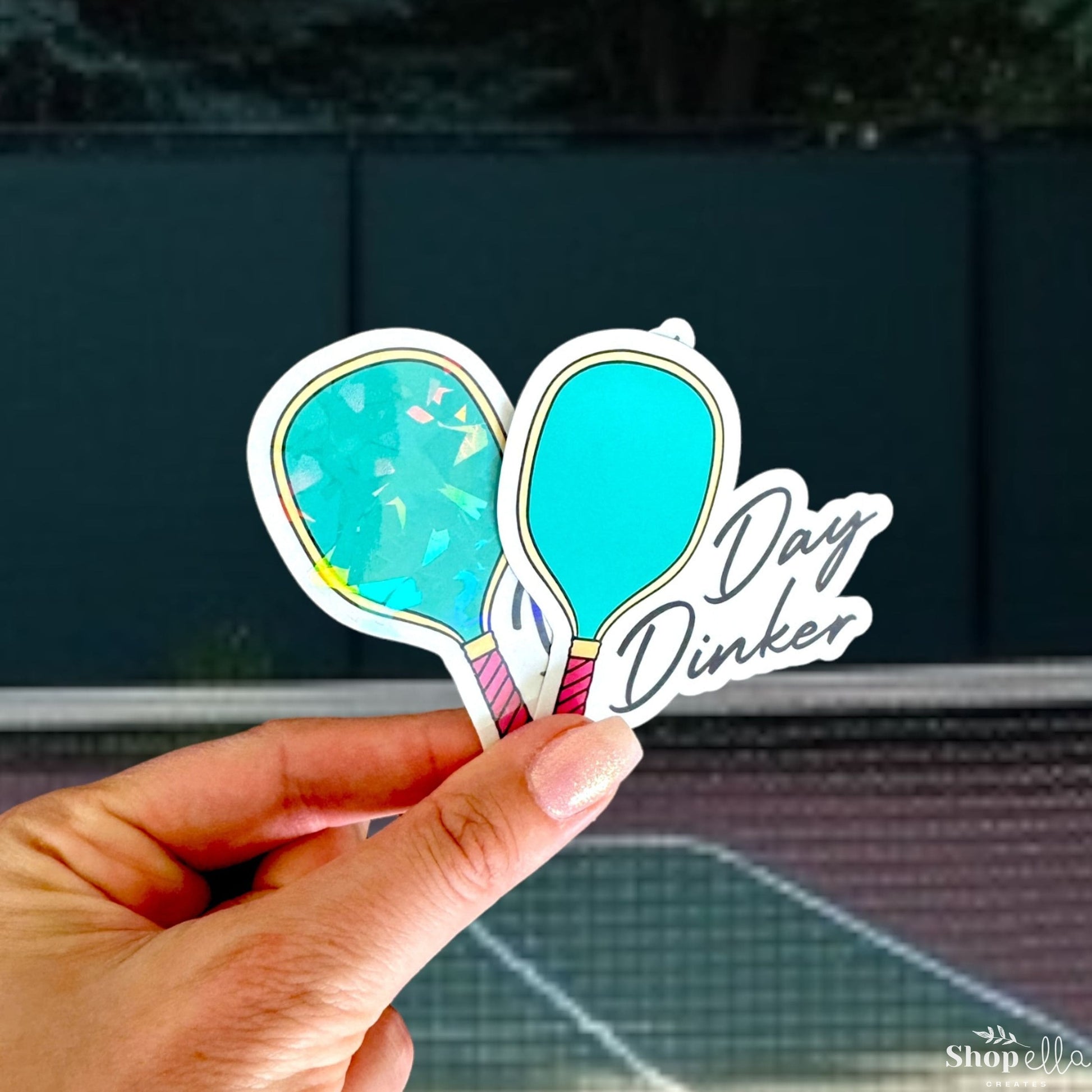 a hand holding up a sticker with a tennis racket on it