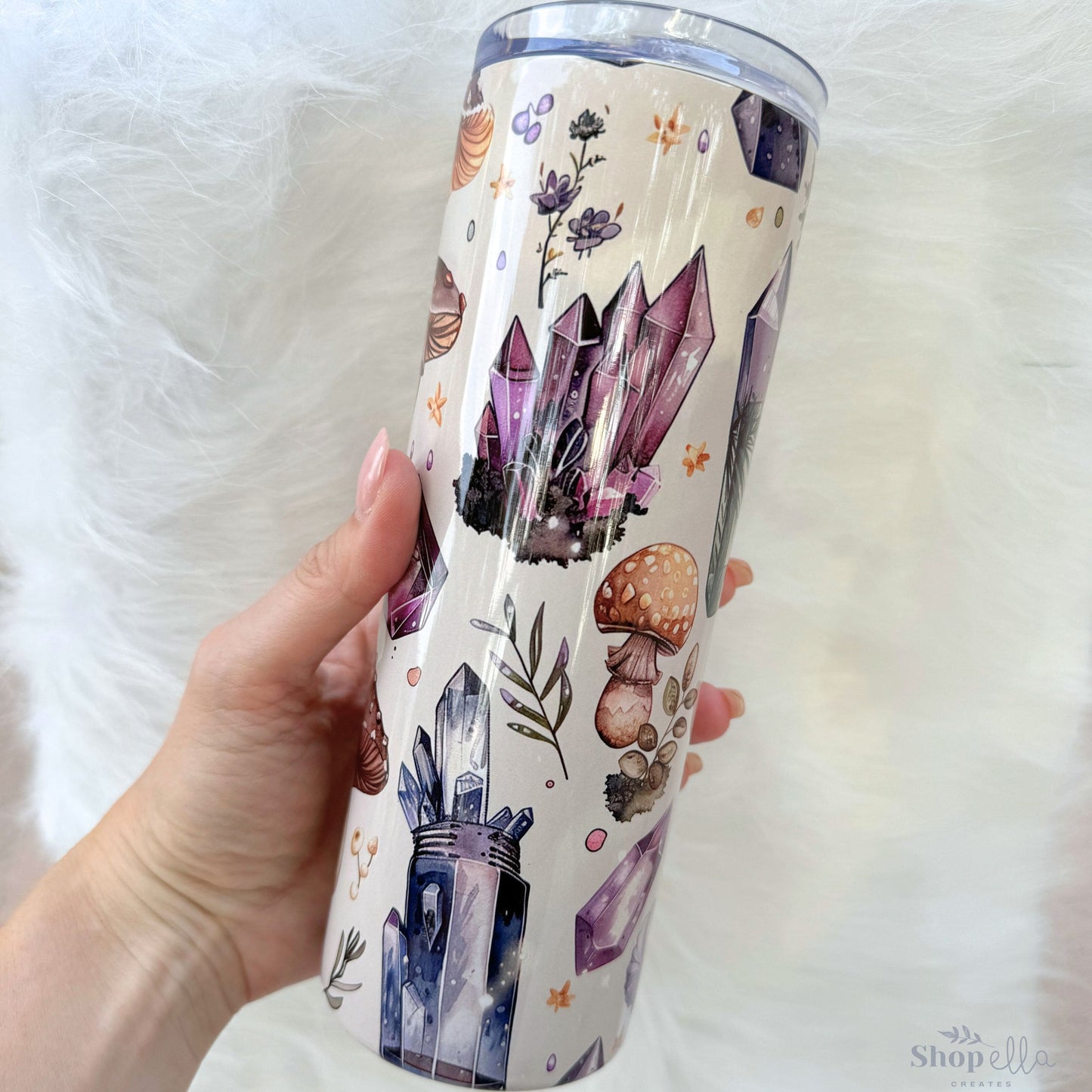 a hand holding a tumbler cup with a design on it