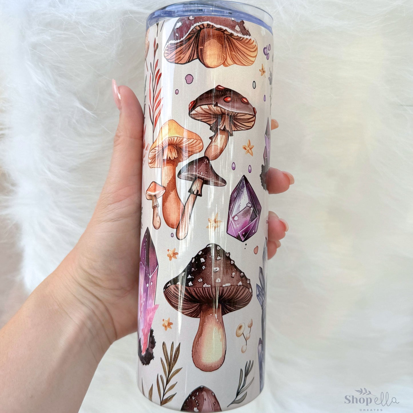a hand holding a cup with a pattern of mushrooms on it