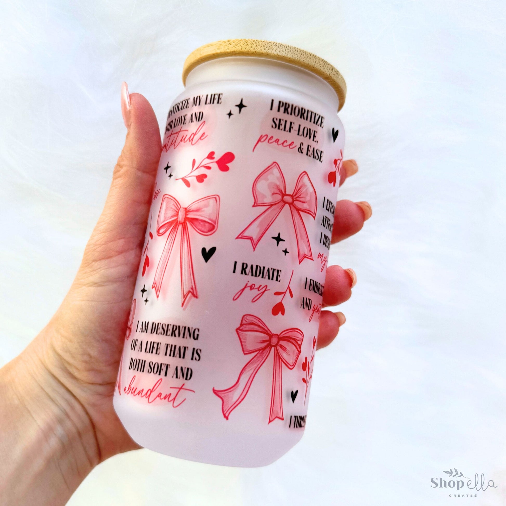 a hand holding a white can with red bows on it