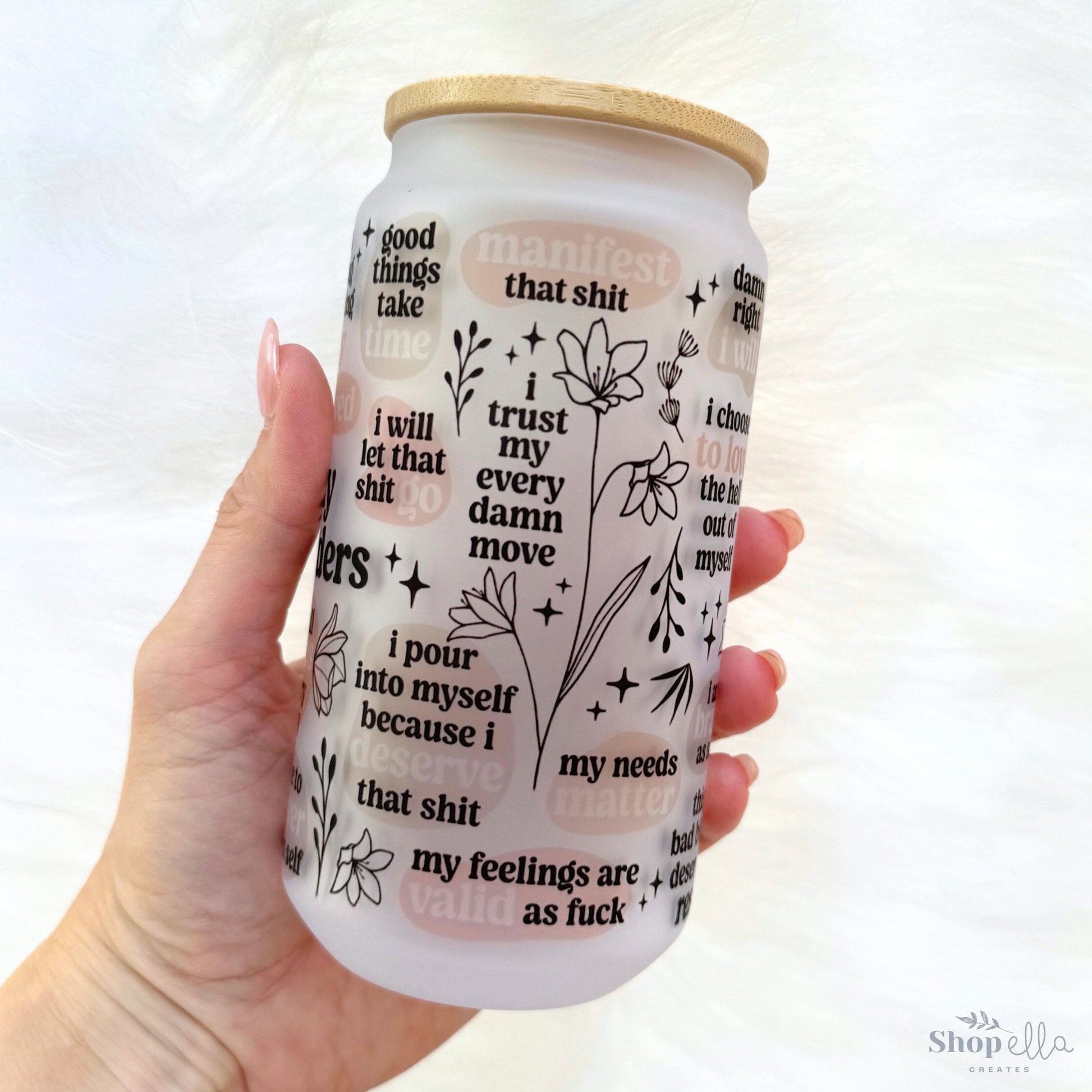 a hand holding a white coffee cup with writing on it
