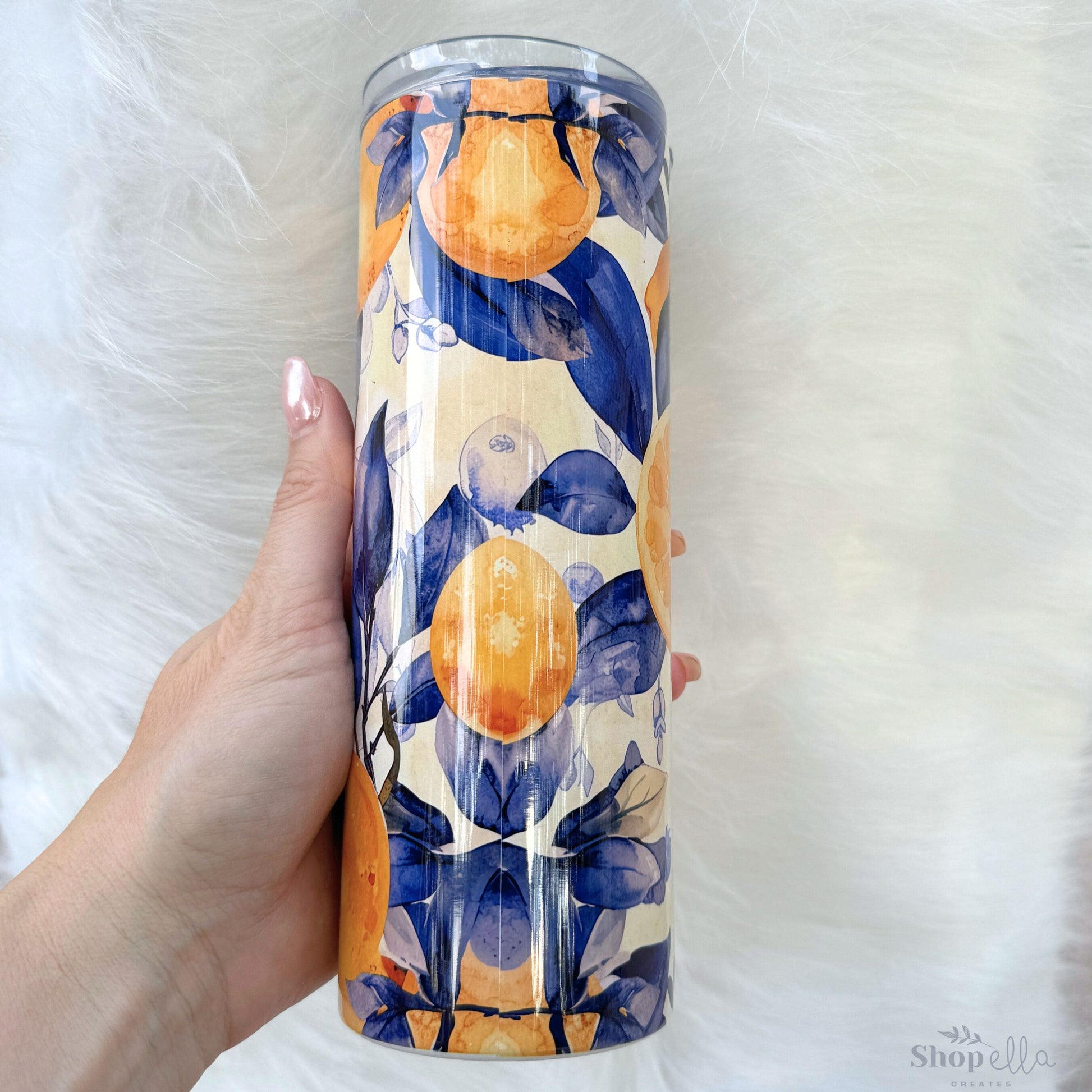 a hand holding a tumbler cup with a painting on it