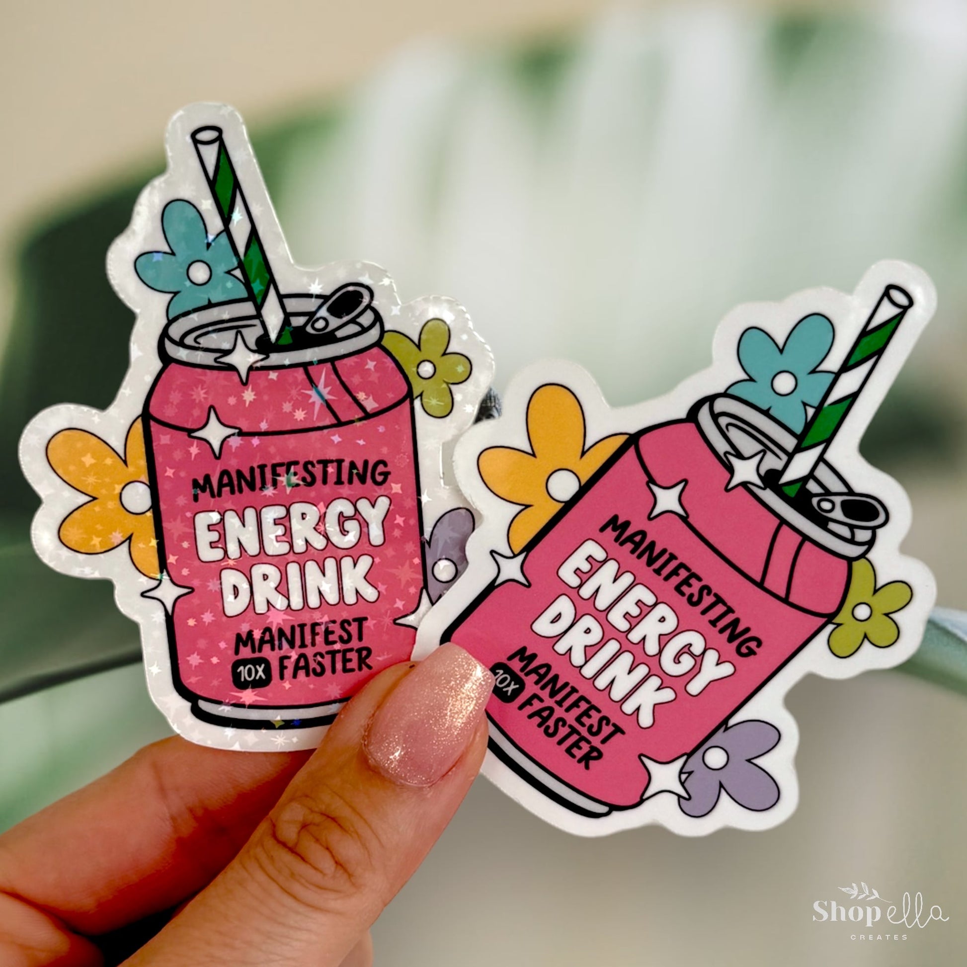 a sticker of a pink drink with a green straw that says manifesting energy drink manifest 10x faster