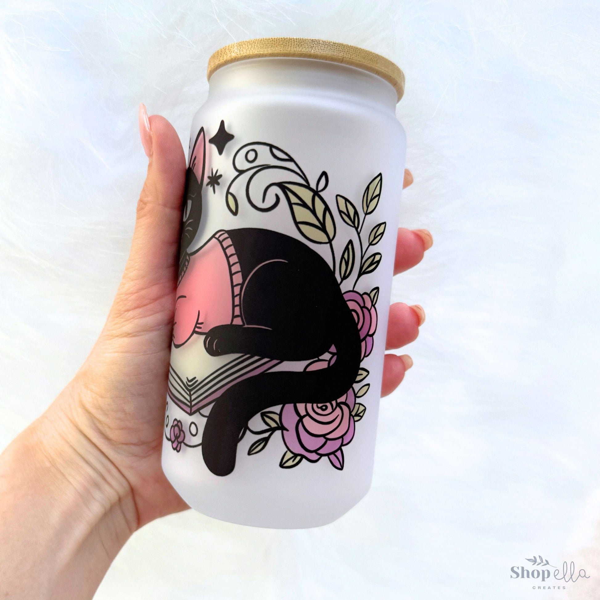 a hand holding a white can with a black cat on it