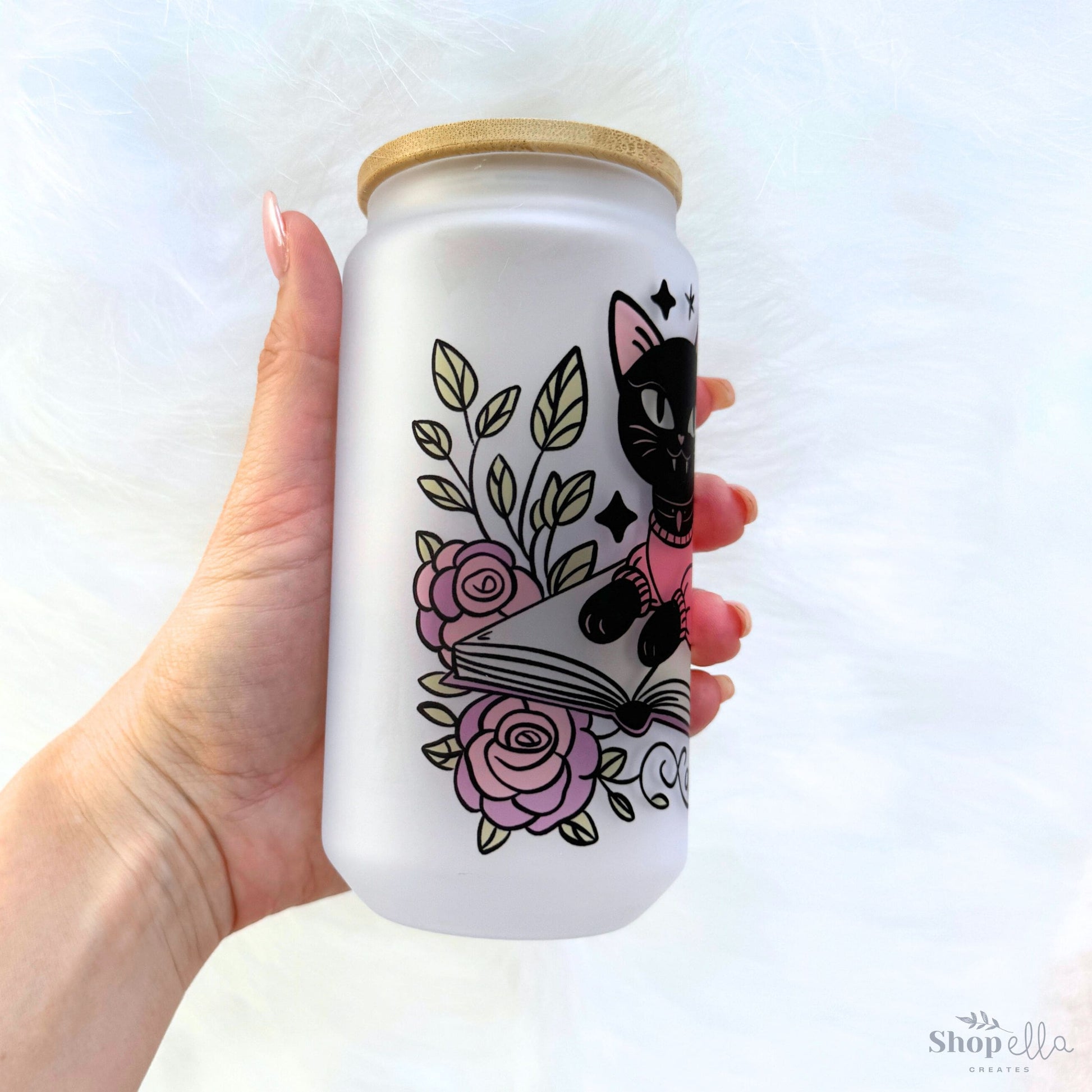 a hand holding a white can with a black cat on it