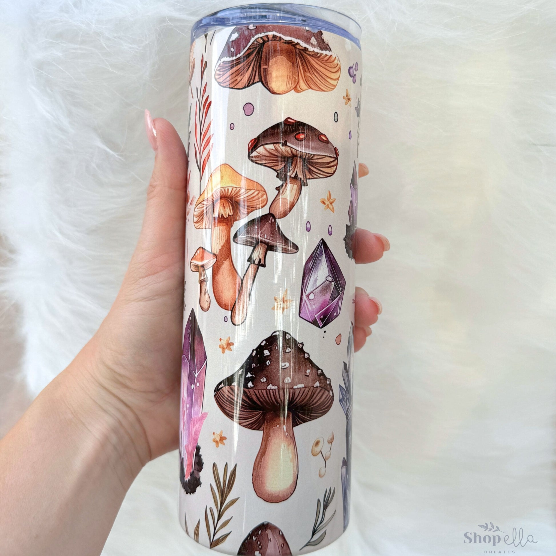 a person holding a cup with a pattern of mushrooms on it