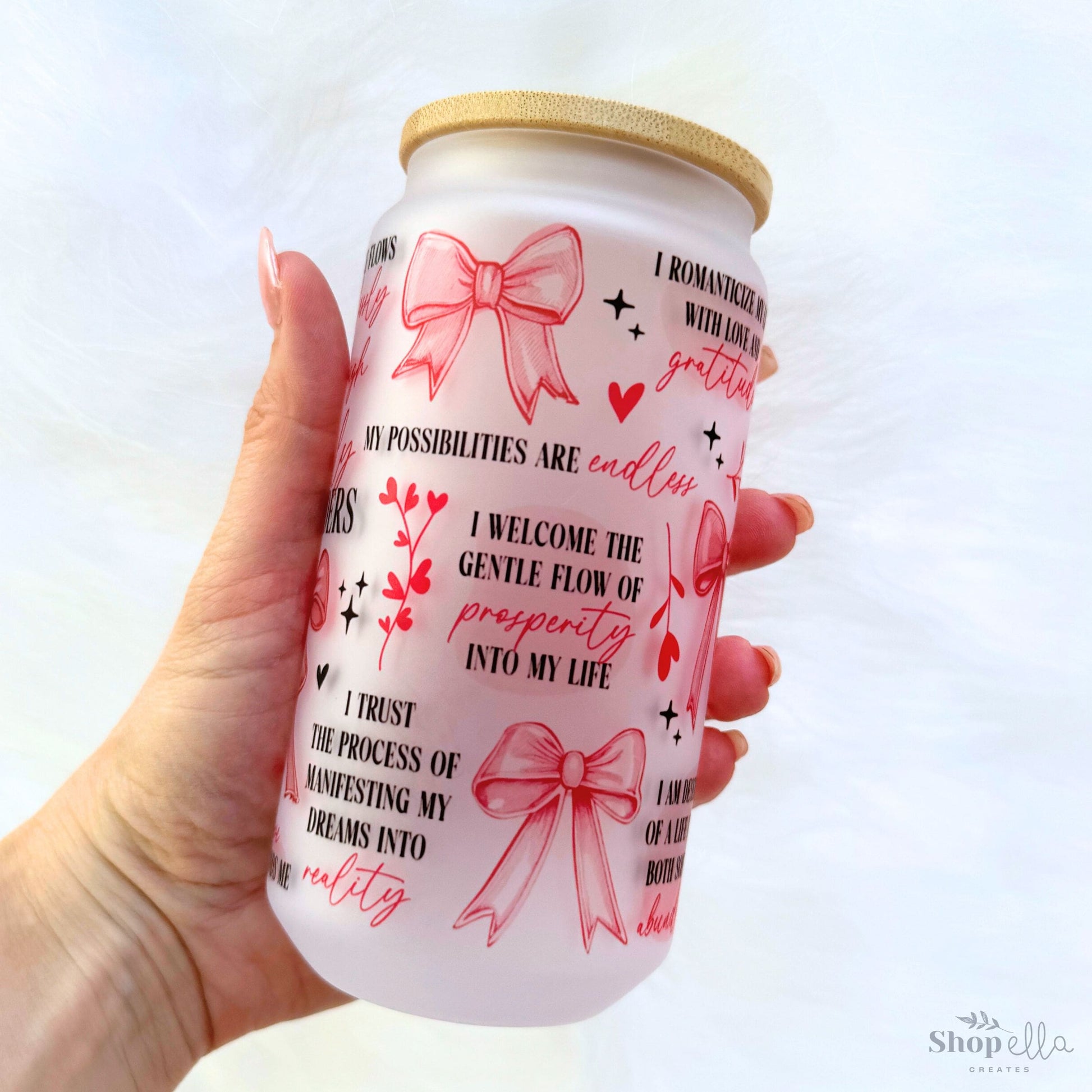 a hand holding a can with a pink bow on it