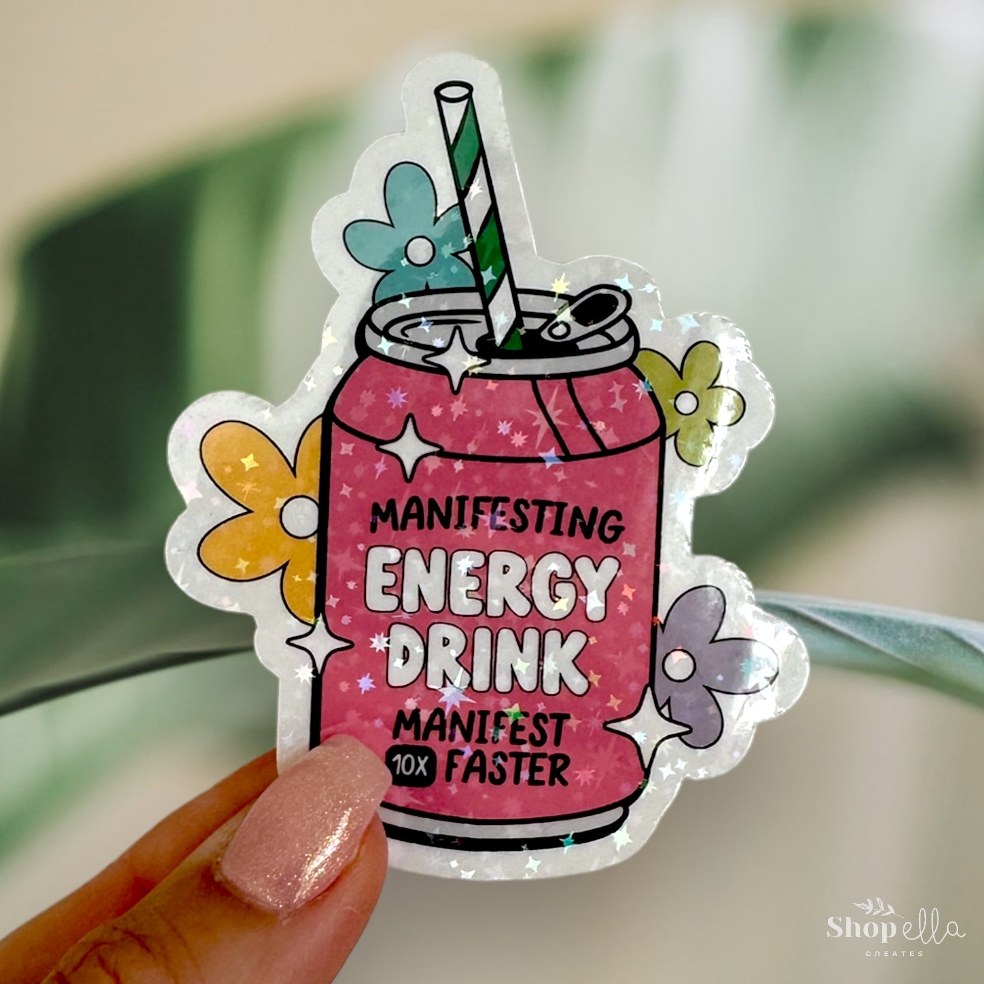 a sticker of a pink drink with a green straw that says manifesting energy drink manifest 10x faster